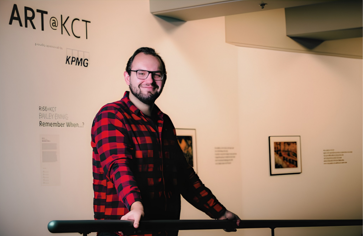 An artist stands smiling in front of his art exhibit at Kelowna Community Theatre.