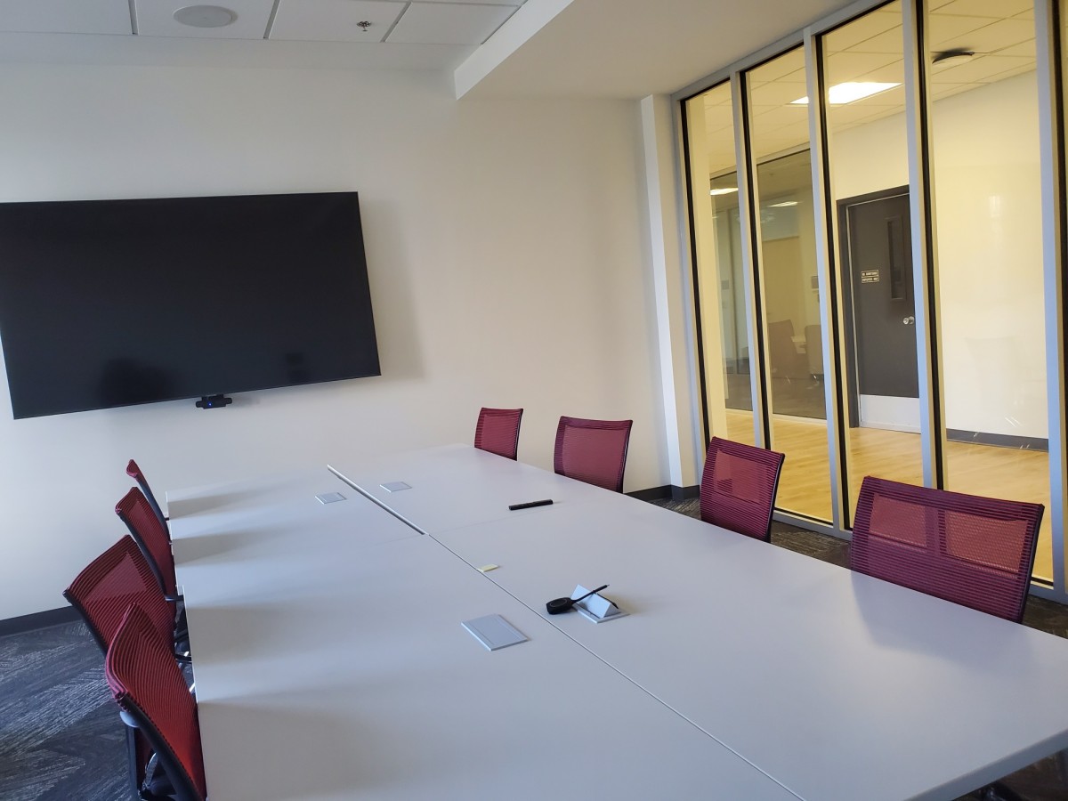 Image of Meeting Room 3&4 with tables, chairs and TV monitor.