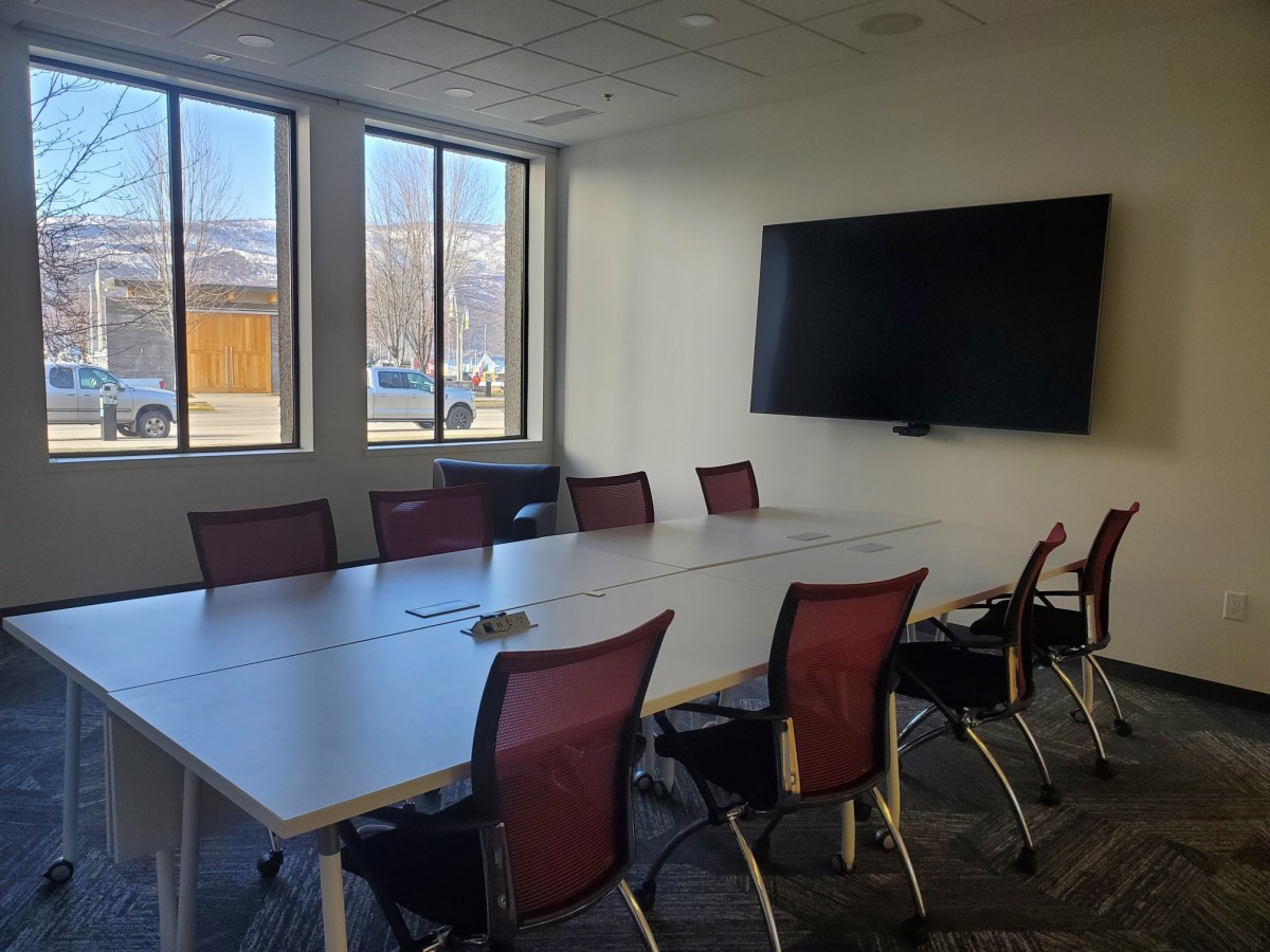 Image of Meeting Room 5 with tables, chairs and a TV monitor in the room.