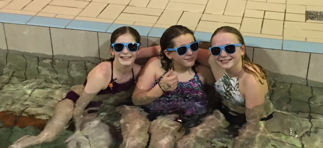 3 youth in the Parkinson Rec Centre pool wearing blue sunglasses and smiling