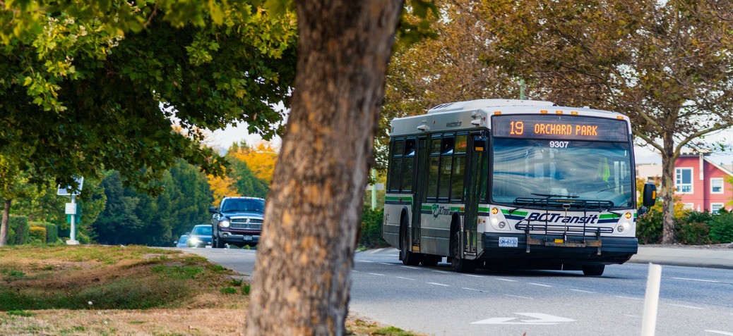 Bus driving along city street with cars behind