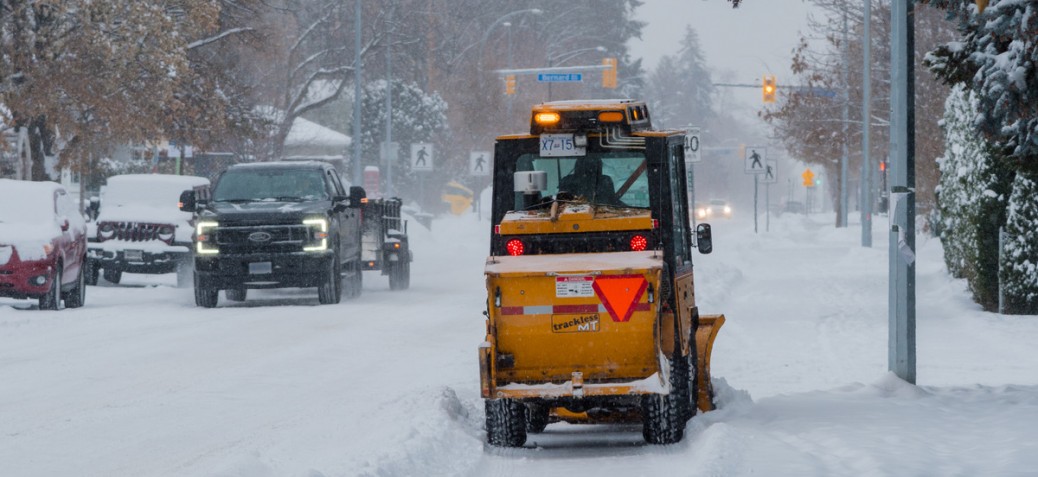 A trackless pusher clears snow down Bernard Avenue.