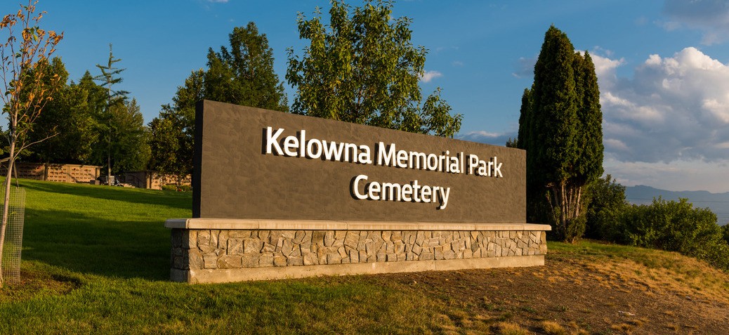 KMPC sign Kelowna Memorial Park Cemetery entry sign at sunset