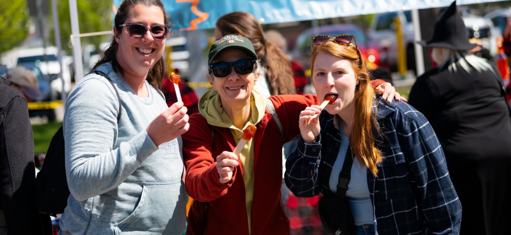 MapleFest 3 people enjoying maple taffy on sticks at the festival