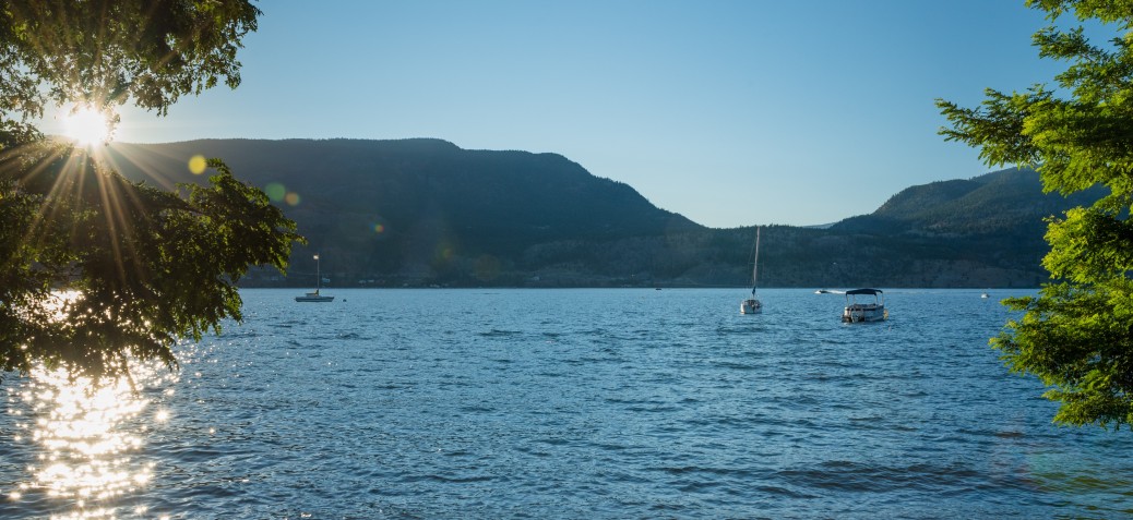 Boat in Okanagan Lake with view from Beach Boat in Okanagan Lake with view from Beach