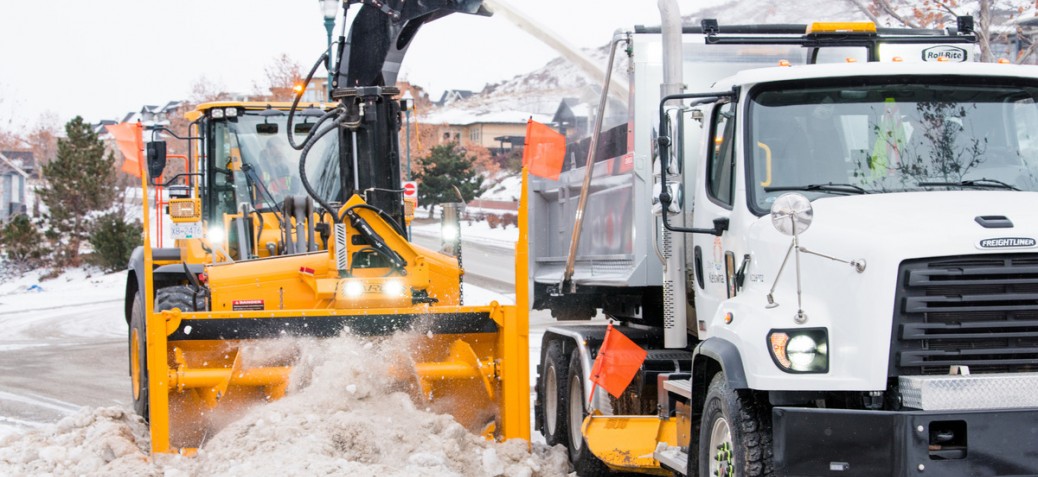 A snowblower blows snow to be hauled away.