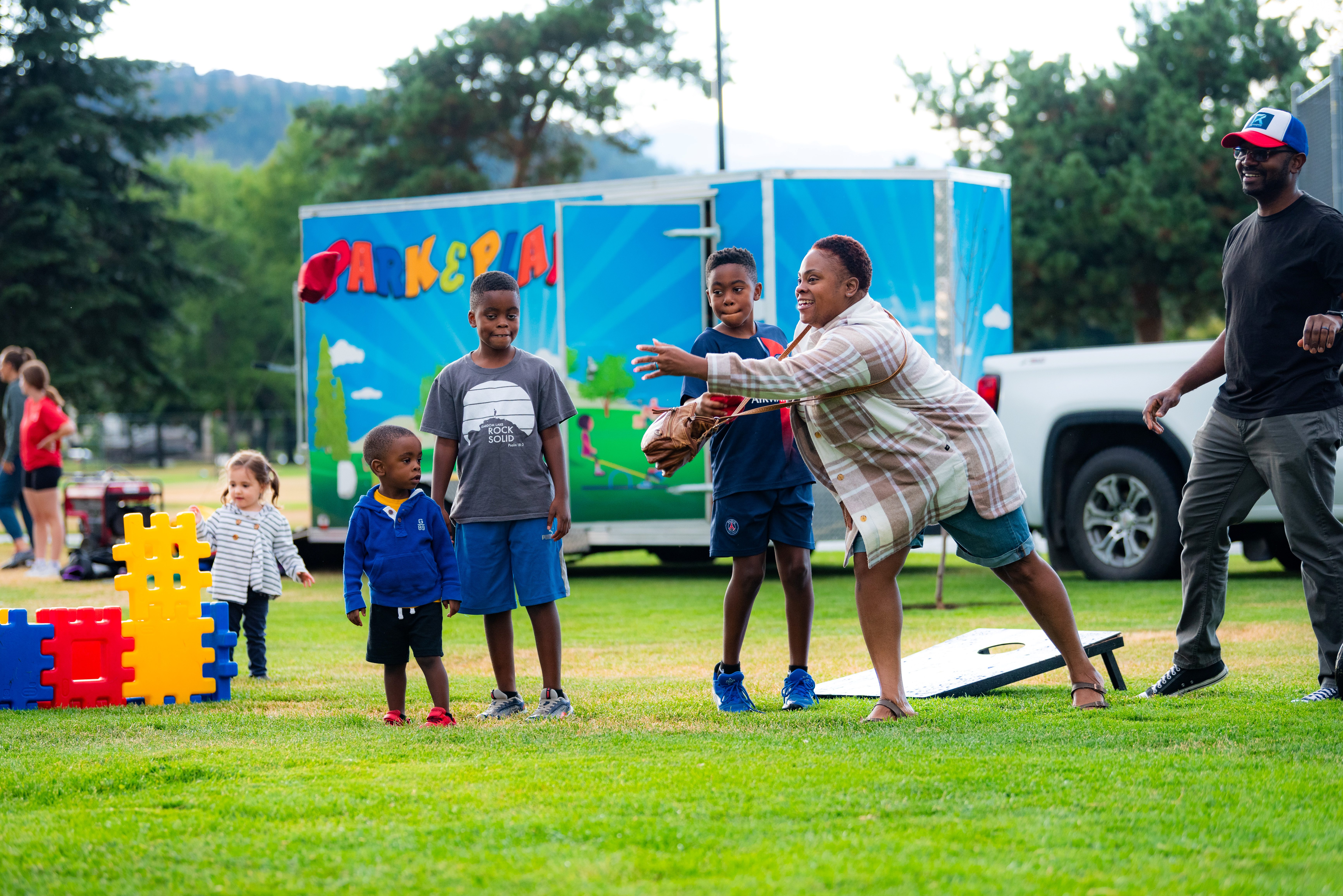 Family playing Corn Hole game at Park & Play Family playing Corn Hole game at Park & Play
